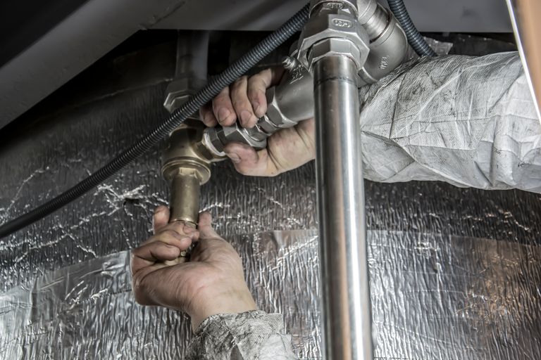 Romo Plumbing - close up of a plumbers hands installing steel pipes indoors showcasing skilled manual work. 6419128 Close-up of a plumber's hands installing steel pipes indoors, showcasing skilled manual work.